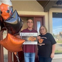 Graduating senior Trey Lefebre holds up his senior sign while standing next to GJHS office staff Karen Provenza.