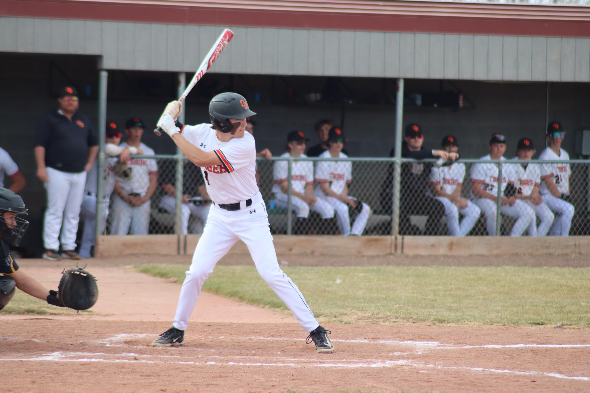 GJHS junior baseball player Clayton Scarbrough stands in the batter’s box. The rest of the GJHS baseball team looks on from the dugout.
