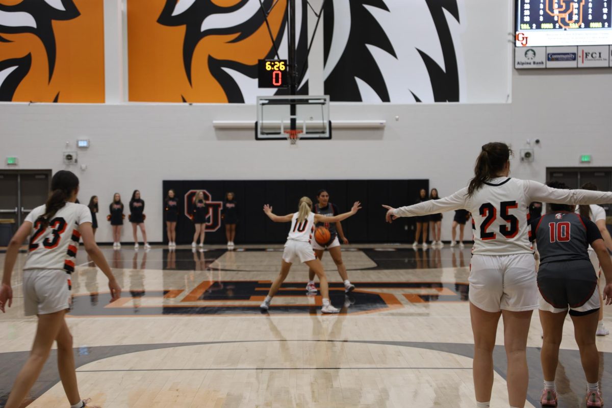 GJHS junior girls' basketball player Bliss Carville guards a Central High School player. Additionally, GJHS senior Ella Alderman and junior Harper Young stand by the hoop.