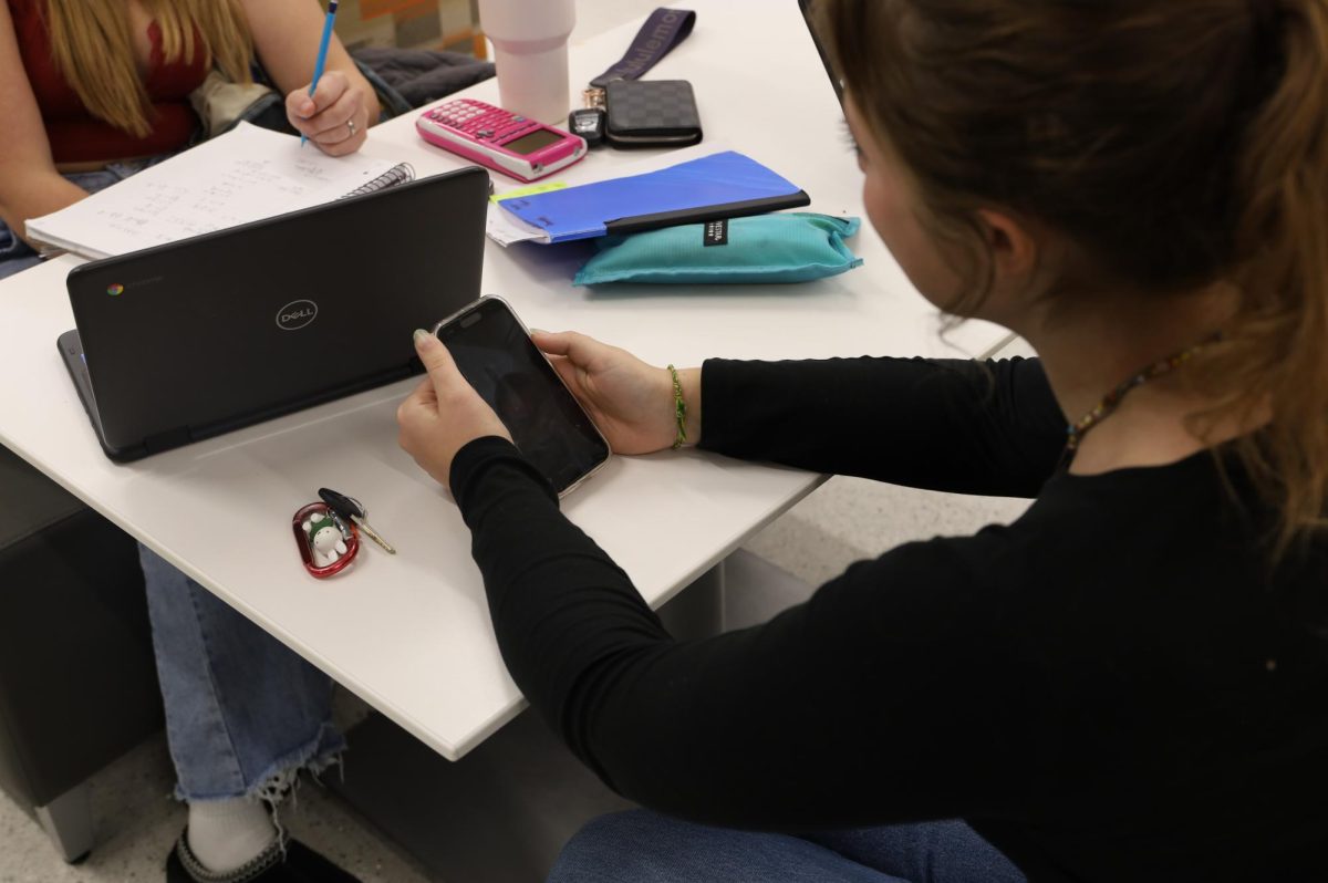 GJHS junior Lauren Ellington uses her phone in the commons. The current cell phone policy for high schoolers is under consideration to be replaced with a bell-to-bell policy.