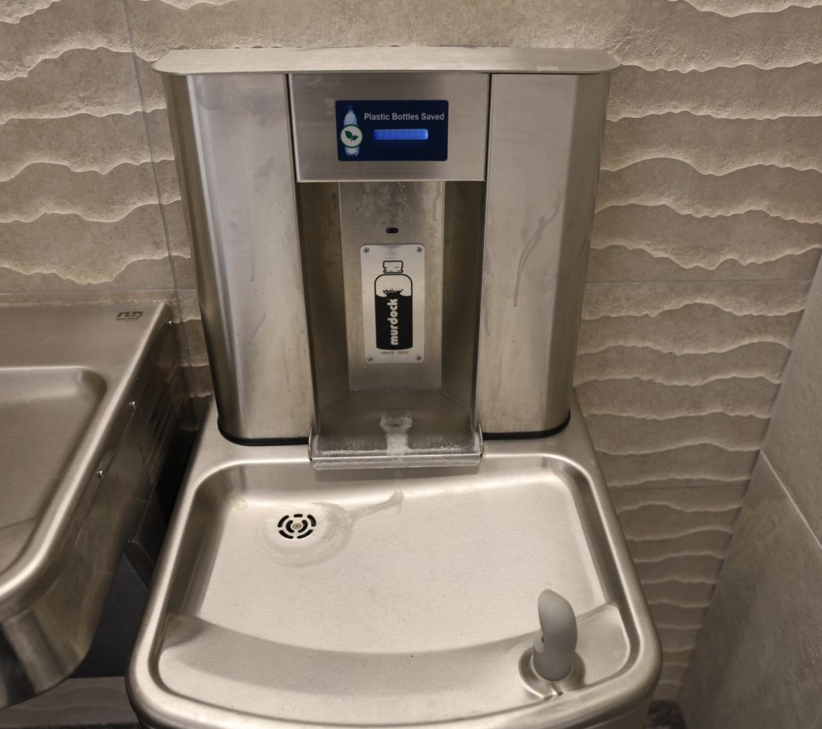This water fountain is found near the entrance to the second level of the main gym. The water fountain is not clean and has several stains.