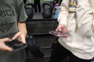 Two girls at GJHS are using their phones instead of talking to each other face-to-face. They were located in the weight room.